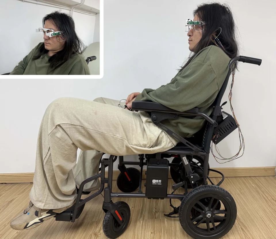 Eye-tracking wheelchair prototype with an inset close-up of the wearable glasses and camera electronics.